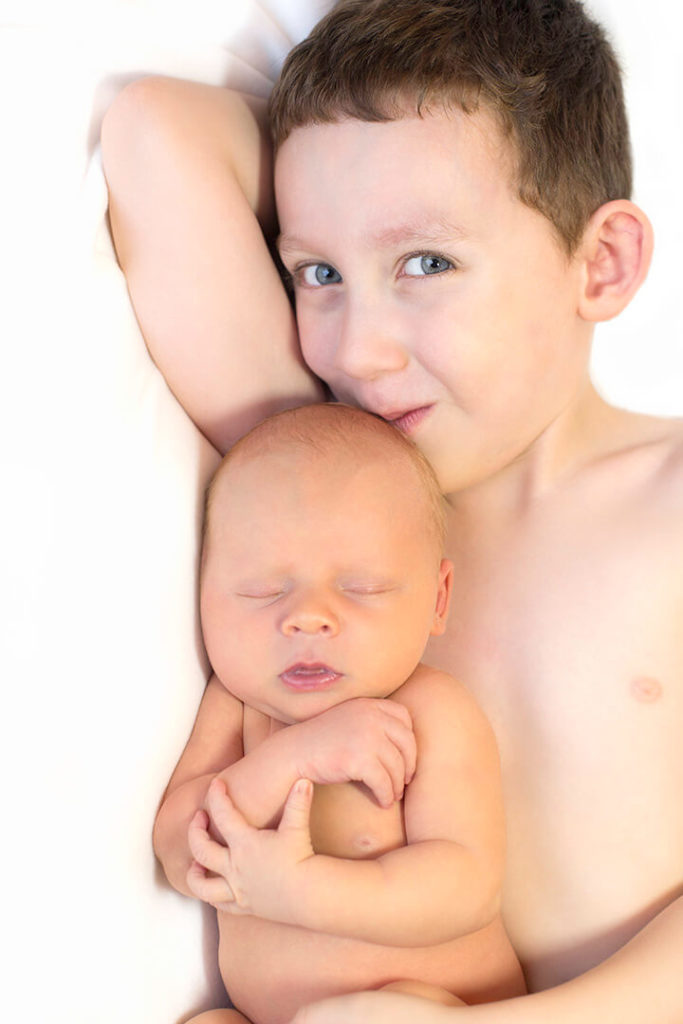 baby and older brother in his arms on a white background